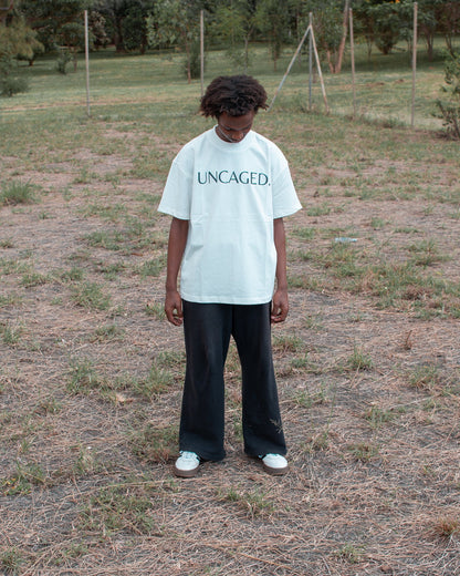 UNCAGED. Origin Tee in off-white — heavyweight oversized fit with tonal logo print.