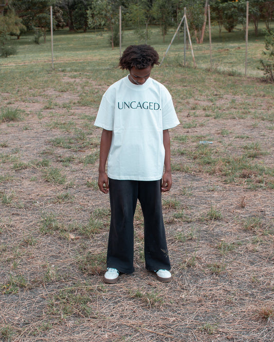 UNCAGED. Origin Tee in off-white — heavyweight oversized fit with tonal logo print.