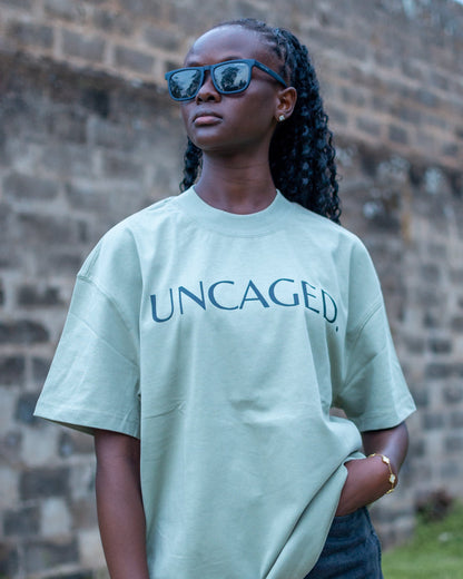 UNCAGED. Origin Tee in sage green ,heavyweight oversized fit with logo print.